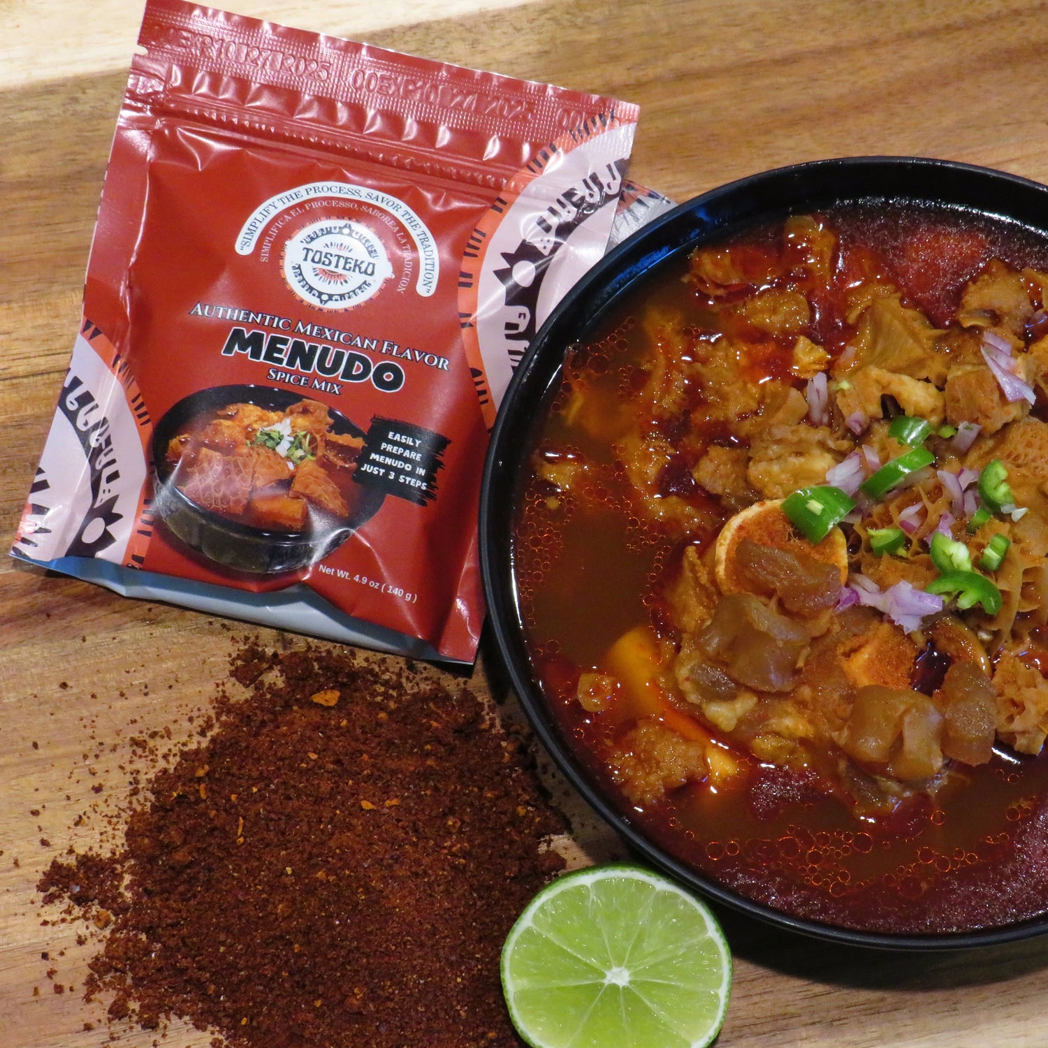 Bowl of menudo with a package labeled 'Menudo' on a wooden surface.